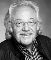 Black and white portrait of a person with curly hair wearing a striped shirt and dark jacket.