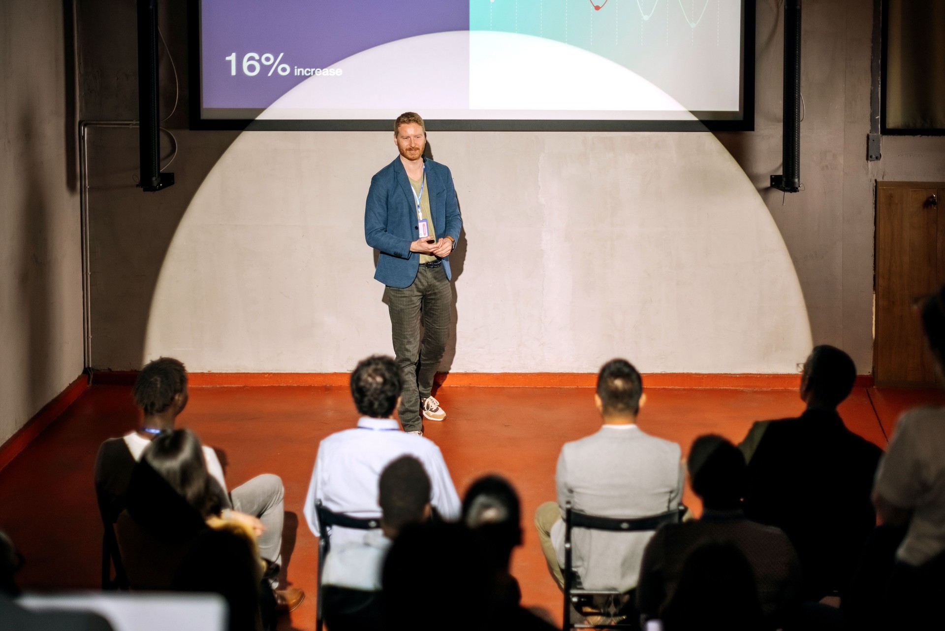 Young casually clothed speaker holding a presentation in front of a crowd